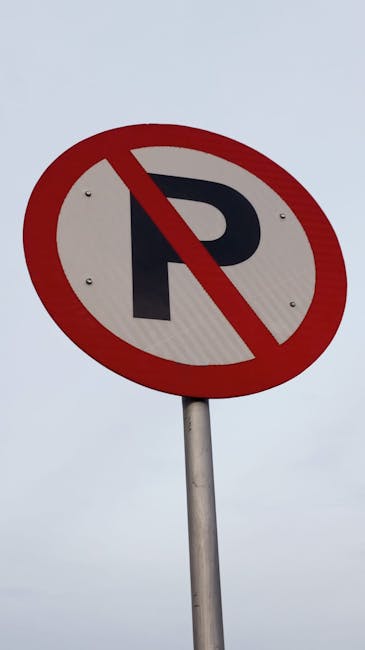 Close-up of a circular 'No Parking' sign mounted on a metal pole against an overcast sky. The sign features a black capital letter 'P' within a white background, enclosed by a red circle with a diagon